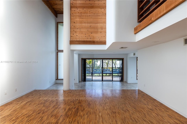 unfurnished living room featuring wood-type flooring, a high ceiling, and wooden ceiling