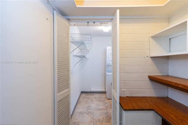 walk in closet featuring stacked washing maching and dryer and light tile patterned floors