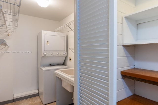 laundry area with sink and stacked washer / drying machine