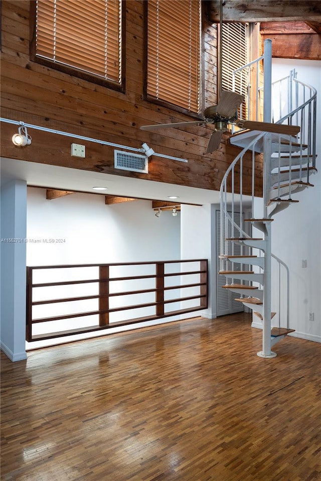 staircase featuring wood walls, hardwood / wood-style flooring, and a high ceiling