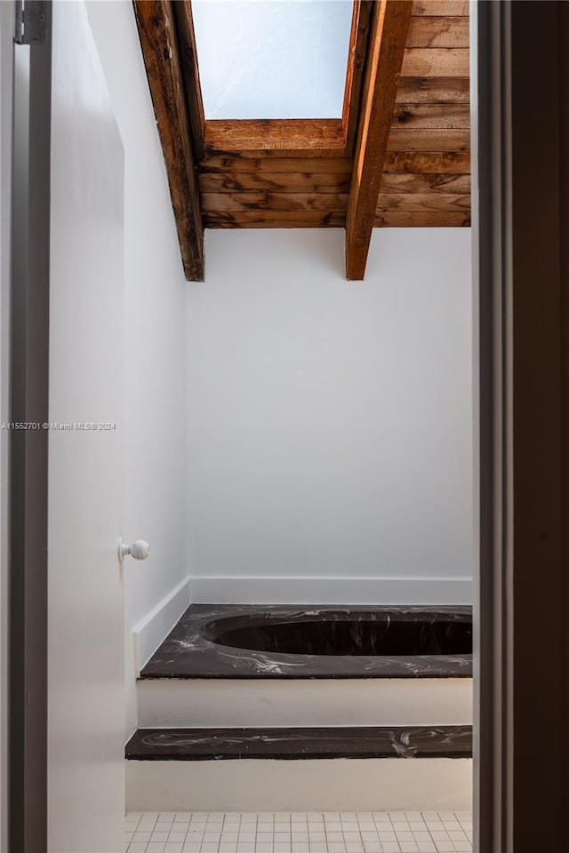 bathroom with a skylight and beam ceiling