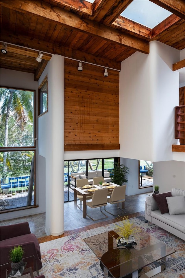 living room with high vaulted ceiling, wood ceiling, a skylight, and beam ceiling