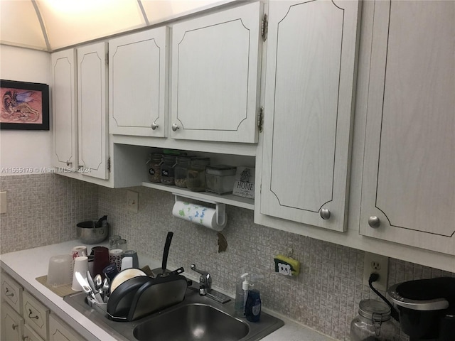 kitchen featuring white cabinets, backsplash, and sink