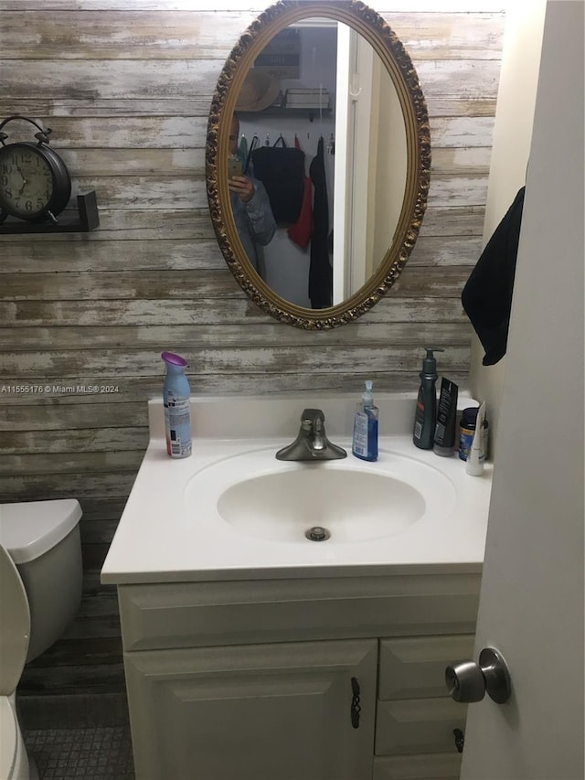 bathroom with wooden walls, oversized vanity, and toilet