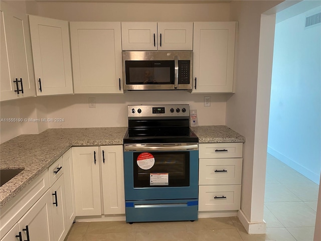 kitchen featuring white cabinets, appliances with stainless steel finishes, light tile floors, and light stone counters