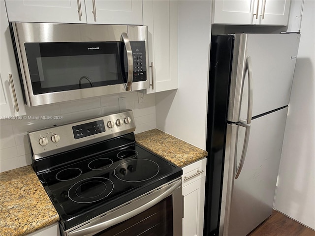 kitchen featuring appliances with stainless steel finishes, white cabinetry, tasteful backsplash, and light stone counters