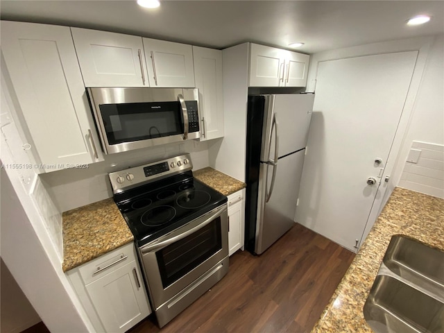 kitchen featuring stainless steel appliances, dark wood-type flooring, white cabinets, light stone counters, and sink