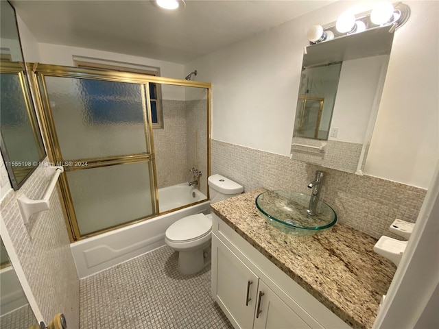 full bathroom featuring vanity, tile flooring, toilet, shower / bath combination with glass door, and tasteful backsplash