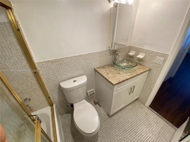 full bathroom featuring tile walls, tile flooring, vanity with extensive cabinet space, toilet, and tasteful backsplash