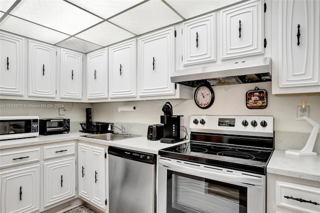 kitchen with a paneled ceiling, white cabinetry, wall chimney exhaust hood, stainless steel dishwasher, and electric range oven