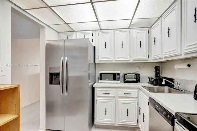 kitchen featuring sink, a drop ceiling, white cabinets, and appliances with stainless steel finishes