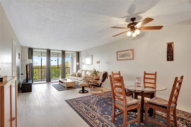 dining area featuring a textured ceiling, ceiling fan, a wall of windows, and hardwood / wood-style floors