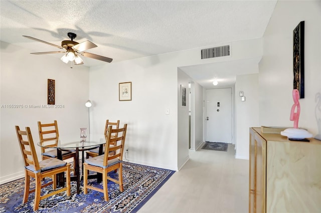 dining space with ceiling fan, a textured ceiling, and hardwood / wood-style flooring