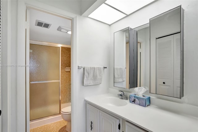 bathroom featuring vanity with extensive cabinet space, a shower with shower door, and toilet