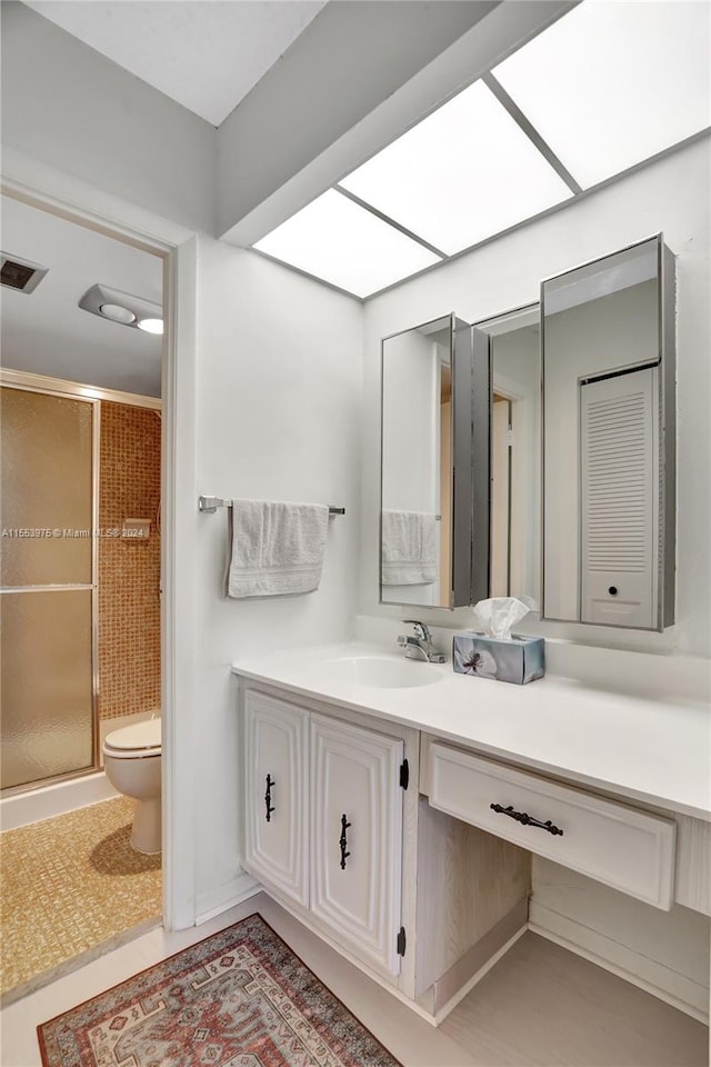 bathroom with tile floors, a shower with door, vanity, and toilet