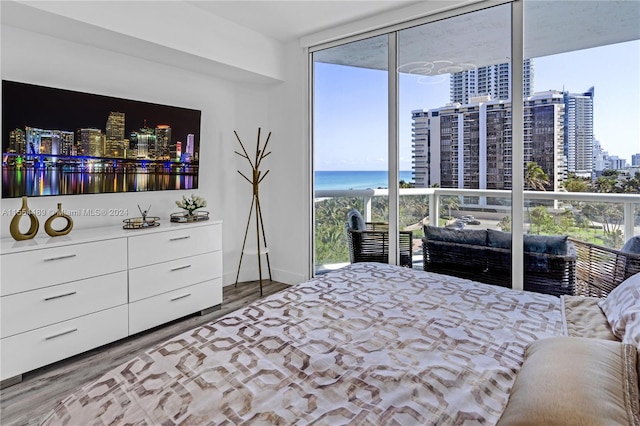 bedroom with a water view, floor to ceiling windows, and hardwood / wood-style floors