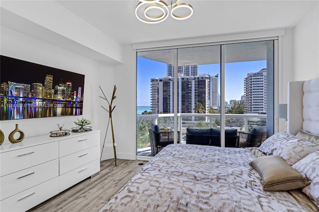 bedroom with light hardwood / wood-style floors, expansive windows, and a chandelier