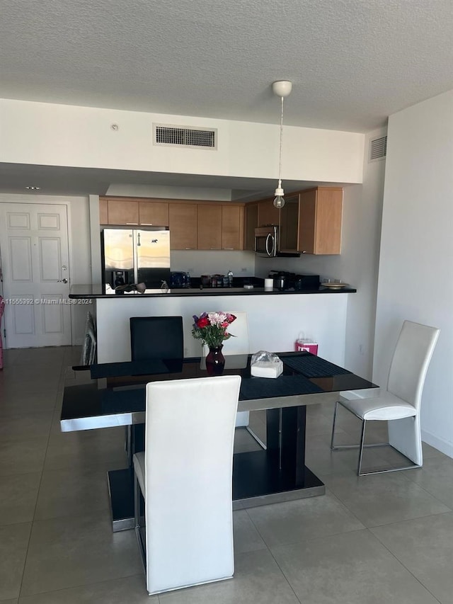 dining space featuring a textured ceiling and light tile flooring