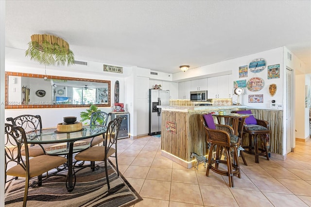 kitchen with light tile flooring, stainless steel appliances, kitchen peninsula, and white cabinetry