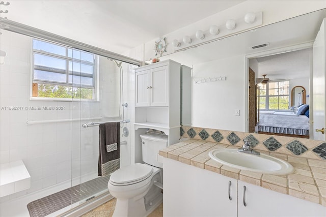 bathroom with a shower with shower door, ceiling fan, oversized vanity, toilet, and tasteful backsplash