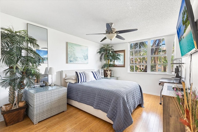 bedroom featuring a textured ceiling, ceiling fan, and light wood-type flooring