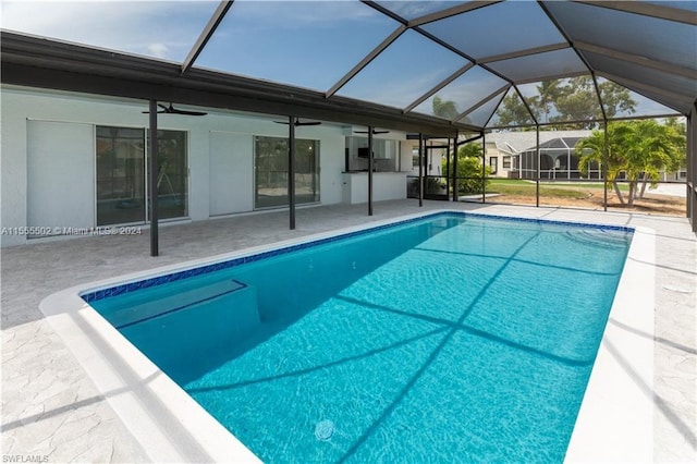 view of swimming pool featuring ceiling fan, a lanai, and a patio area