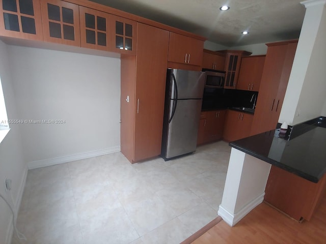 kitchen with kitchen peninsula, light tile flooring, sink, and stainless steel appliances