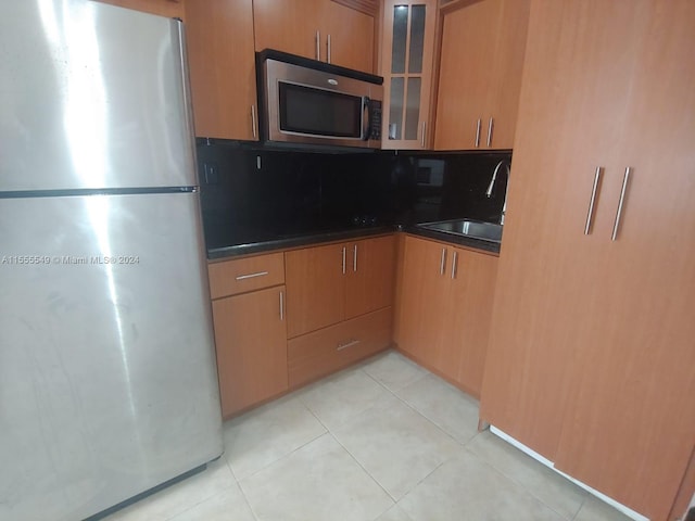 kitchen featuring tasteful backsplash, light tile floors, appliances with stainless steel finishes, and sink