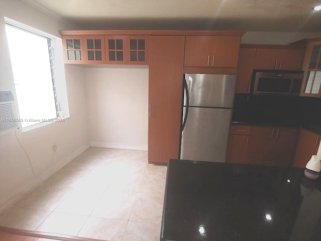 kitchen featuring a healthy amount of sunlight, light tile floors, and stainless steel refrigerator