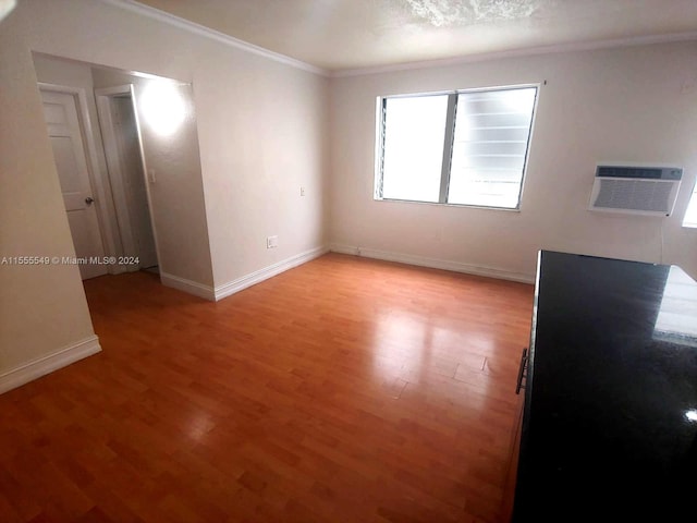 empty room with an AC wall unit, ornamental molding, and light hardwood / wood-style floors