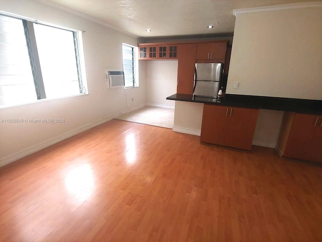 kitchen featuring a wall mounted air conditioner, light hardwood / wood-style floors, stainless steel refrigerator, and ornamental molding