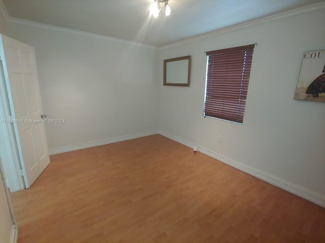 spare room featuring ornamental molding and light hardwood / wood-style flooring