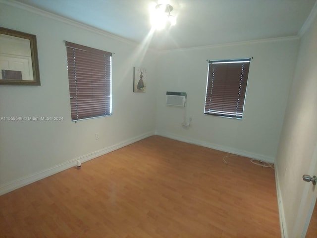 empty room featuring a wall unit AC, ornamental molding, and light wood-type flooring