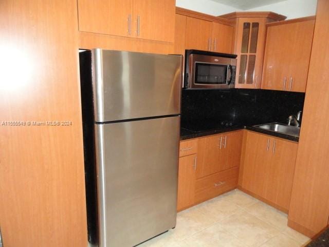 kitchen featuring stainless steel appliances, light tile flooring, and sink