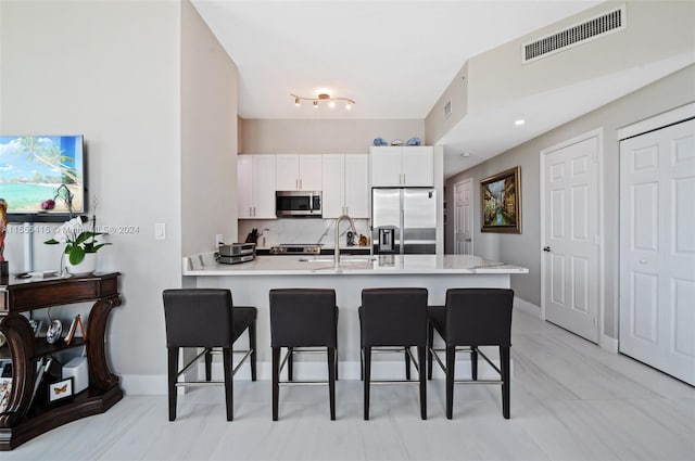 kitchen featuring light tile floors, kitchen peninsula, appliances with stainless steel finishes, white cabinets, and sink