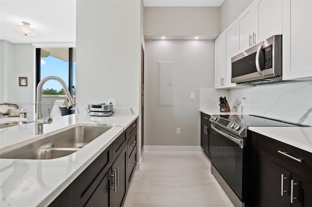 kitchen with light stone countertops, sink, stainless steel appliances, white cabinets, and tasteful backsplash