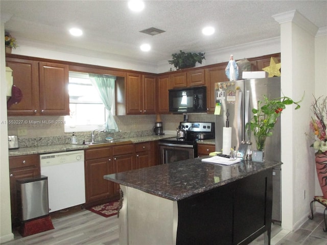 kitchen featuring sink, light wood-type flooring, a textured ceiling, ornamental molding, and stainless steel appliances