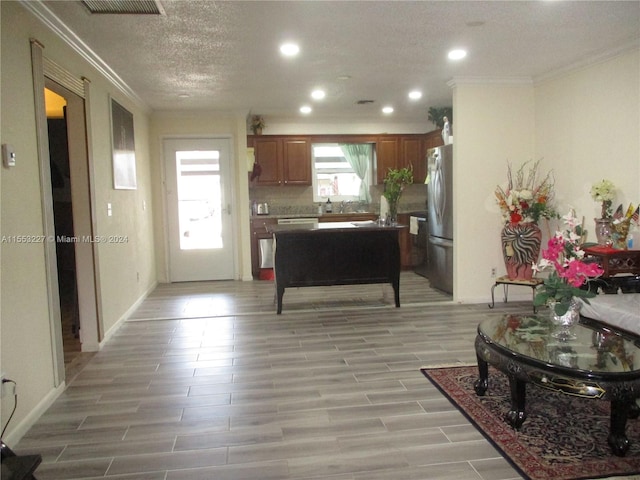 kitchen with ornamental molding, a textured ceiling, stainless steel refrigerator, and light hardwood / wood-style flooring