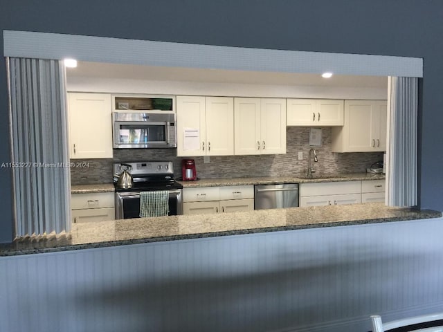 kitchen featuring backsplash, sink, white cabinets, and appliances with stainless steel finishes