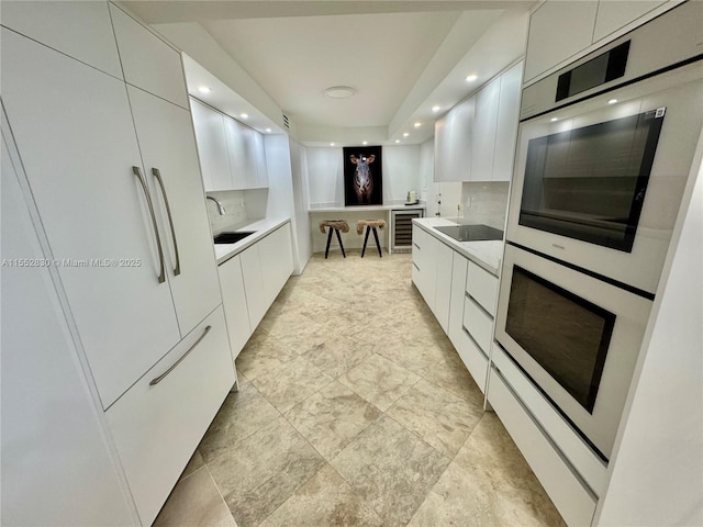 kitchen featuring black electric stovetop, white cabinetry, and tasteful backsplash