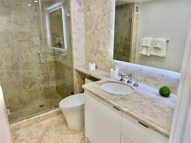 bathroom with toilet, tile walls, a shower with door, and vanity