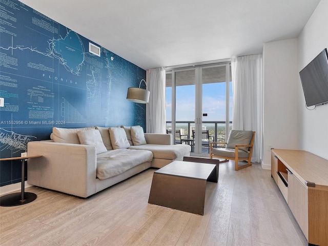 living room with a water view, expansive windows, french doors, and light hardwood / wood-style flooring