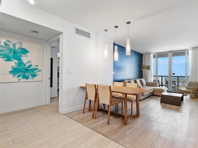 dining space with light hardwood / wood-style floors and a wall of windows