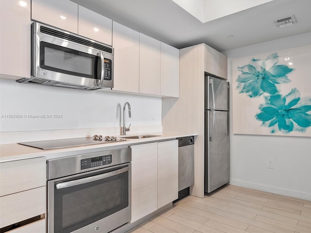 kitchen with white cabinetry, light hardwood / wood-style flooring, sink, and stainless steel appliances