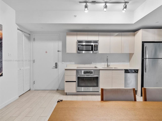 kitchen featuring light hardwood / wood-style floors, stainless steel appliances, track lighting, and sink