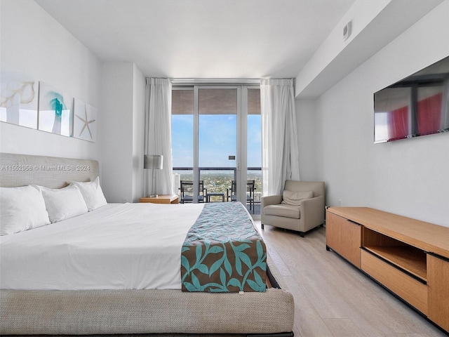 bedroom with a wall of windows, access to outside, and light wood-type flooring