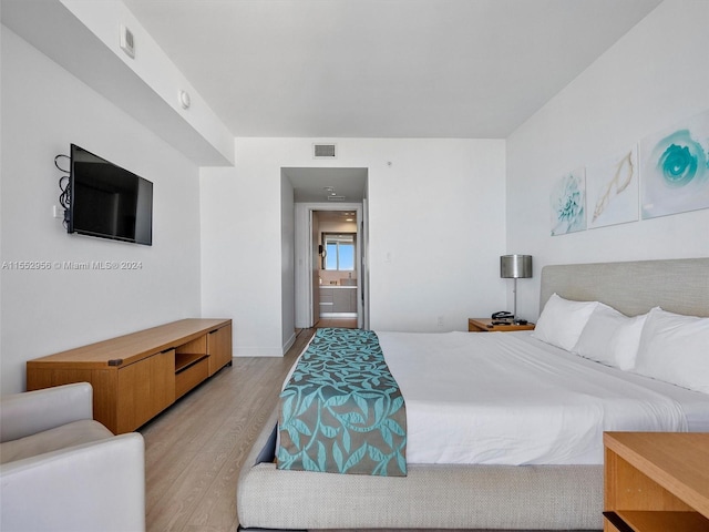 bedroom with ensuite bath and light hardwood / wood-style floors