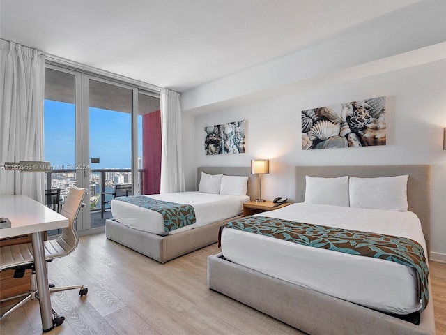 bedroom with access to outside, floor to ceiling windows, and light wood-type flooring