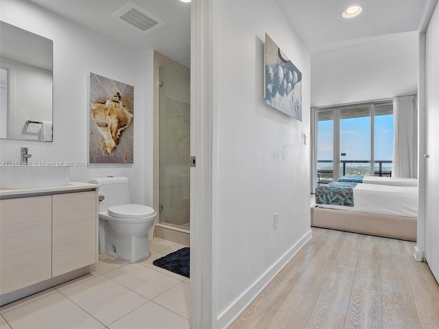 bathroom featuring hardwood / wood-style flooring, vanity, a shower with door, and toilet