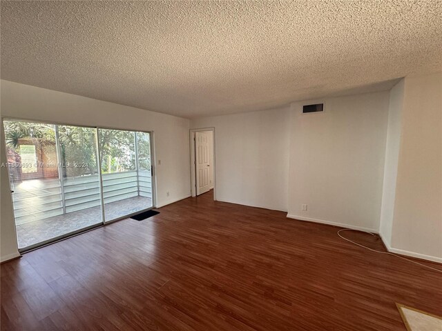 spare room with dark wood-type flooring and a textured ceiling